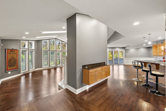 interior space featuring a breakfast bar area, a wealth of natural light, and dark wood-type flooring