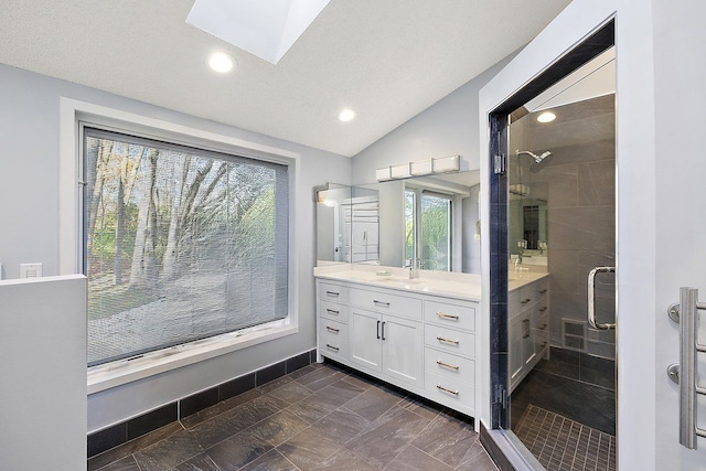 bathroom with vanity, lofted ceiling with skylight, and a shower with door