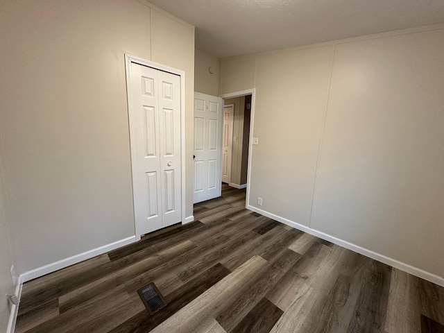 unfurnished bedroom with dark hardwood / wood-style floors, a textured ceiling, and a closet