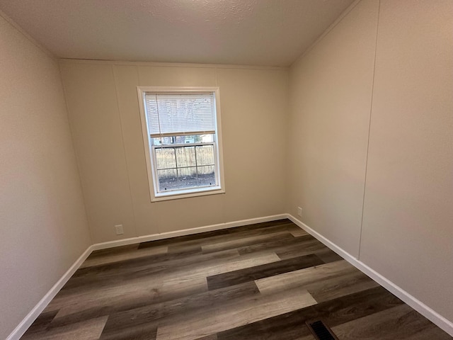 empty room with dark hardwood / wood-style flooring and a textured ceiling