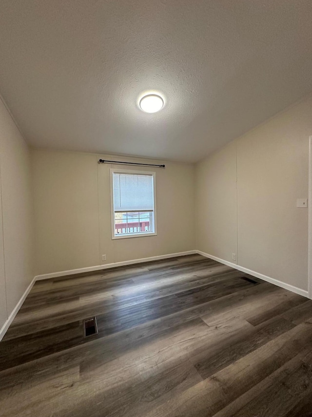 unfurnished room with a textured ceiling and dark hardwood / wood-style floors