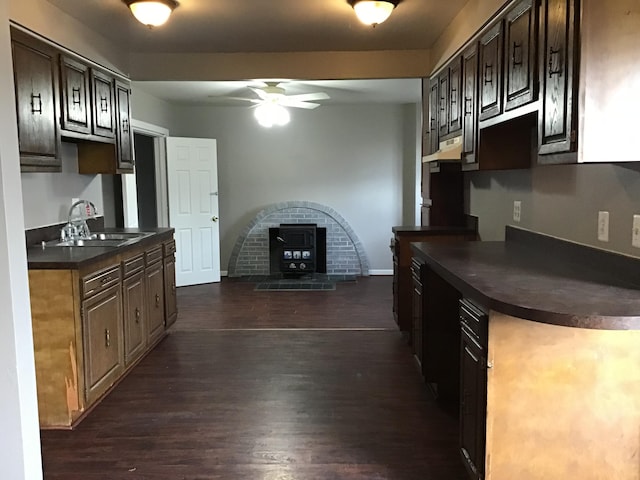 kitchen featuring a wood stove, sink, dark hardwood / wood-style floors, ceiling fan, and dark brown cabinetry