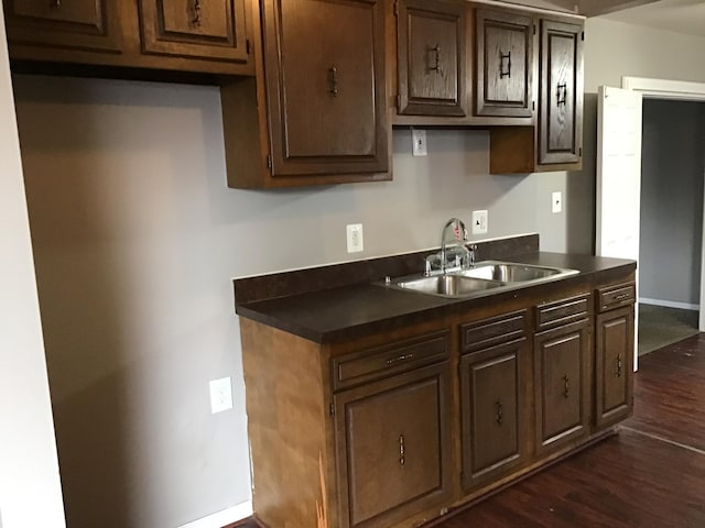 kitchen with dark brown cabinets, dark hardwood / wood-style floors, and sink