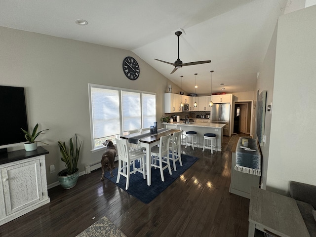 dining area with ceiling fan, sink, dark hardwood / wood-style floors, a baseboard heating unit, and vaulted ceiling