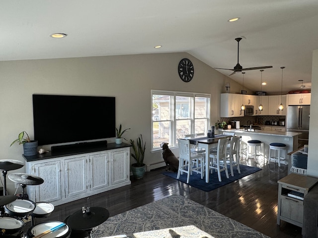 living room featuring baseboard heating, ceiling fan, dark hardwood / wood-style flooring, and vaulted ceiling