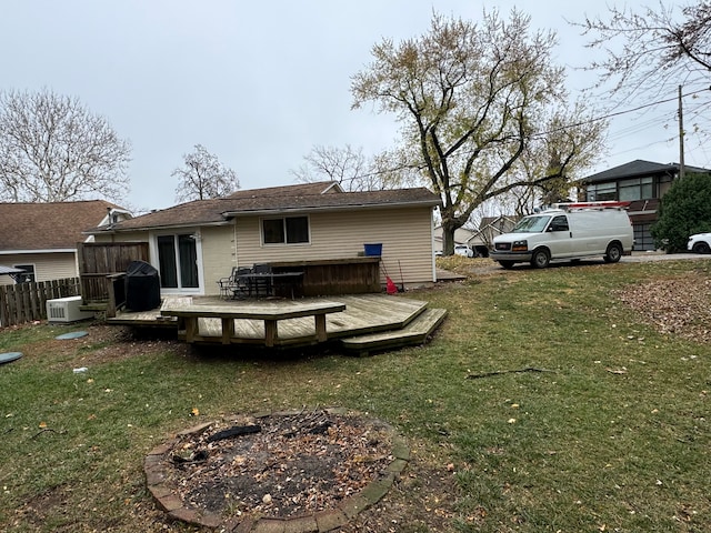 rear view of property featuring a yard, a fire pit, and a deck