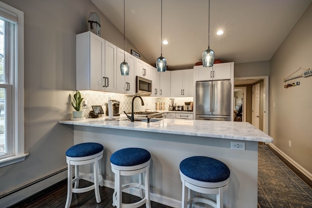 kitchen with pendant lighting, a breakfast bar, a baseboard heating unit, white cabinets, and stainless steel appliances