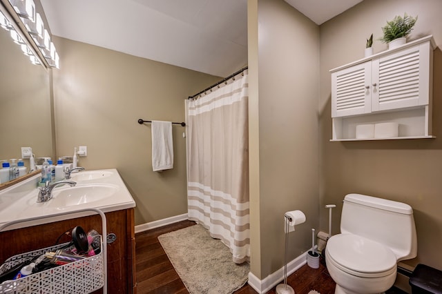 bathroom with wood-type flooring, vanity, toilet, and curtained shower