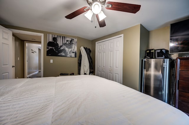 bedroom featuring stainless steel fridge, ceiling fan, and a closet