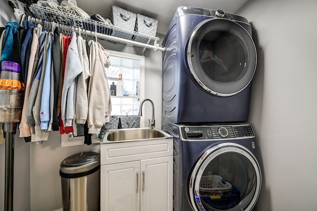 clothes washing area featuring cabinets, sink, and stacked washer and clothes dryer