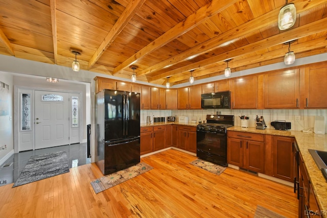 kitchen featuring beam ceiling, light hardwood / wood-style flooring, hanging light fixtures, and black appliances