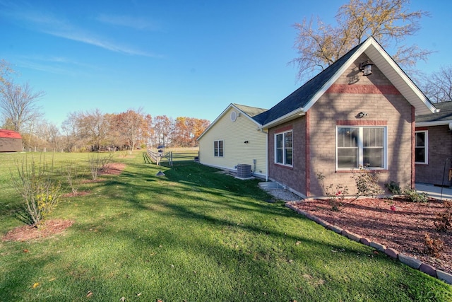 view of side of property with a lawn and central AC