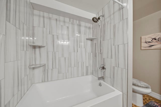 bathroom featuring tiled shower / bath combo and toilet