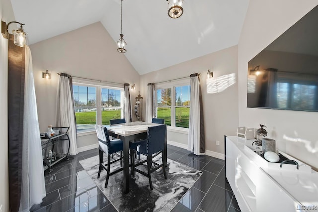 dining space with dark tile patterned floors and high vaulted ceiling