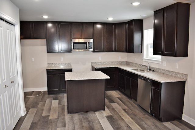 kitchen featuring appliances with stainless steel finishes, dark hardwood / wood-style flooring, a center island, and sink