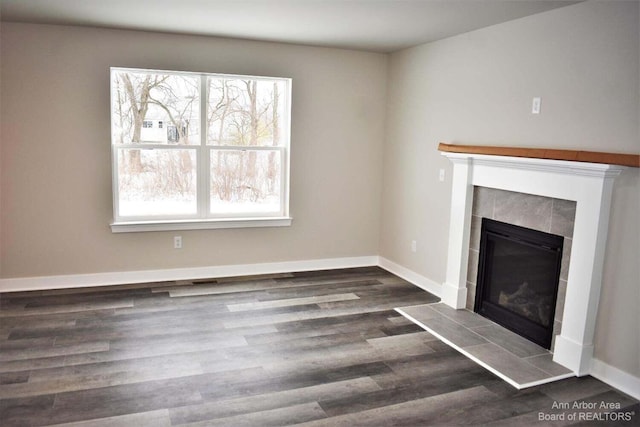 unfurnished living room featuring a tile fireplace and dark hardwood / wood-style flooring