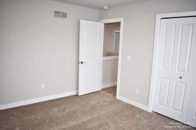 unfurnished bedroom with light carpet and a closet