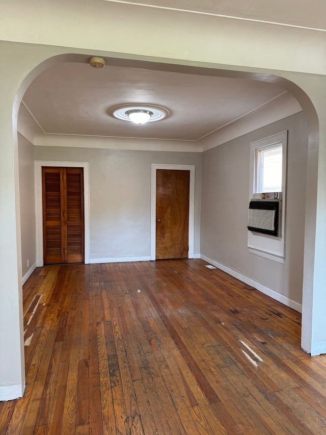 empty room featuring cooling unit, crown molding, and dark wood-type flooring