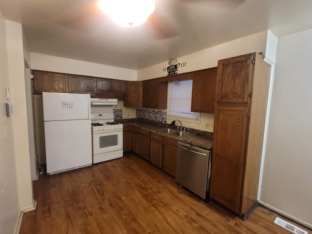 kitchen with dark hardwood / wood-style flooring, white appliances, sink, and tasteful backsplash