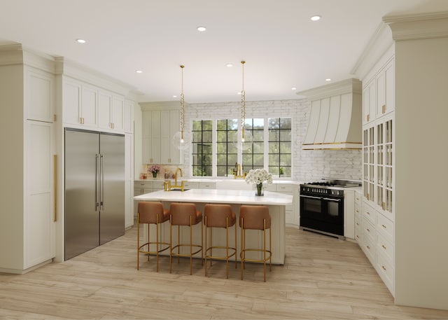 kitchen featuring wall chimney exhaust hood, light hardwood / wood-style floors, decorative light fixtures, high quality appliances, and a kitchen island