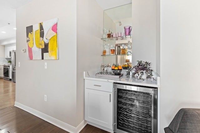 bar featuring dark hardwood / wood-style floors, white cabinetry, stainless steel appliances, and beverage cooler