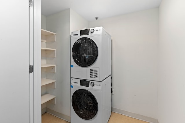 laundry room with stacked washing maching and dryer and light tile patterned flooring