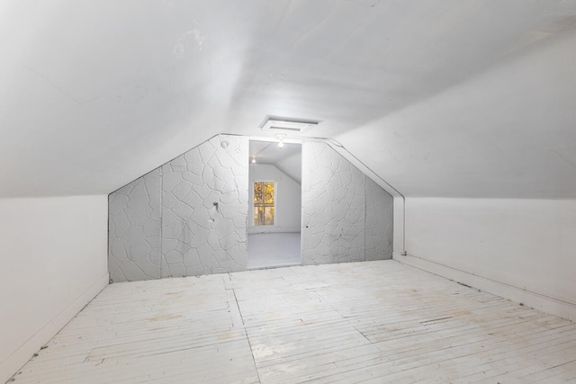 additional living space with vaulted ceiling and light wood-type flooring