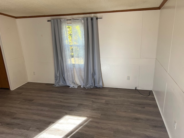 spare room featuring crown molding, dark hardwood / wood-style flooring, and a textured ceiling