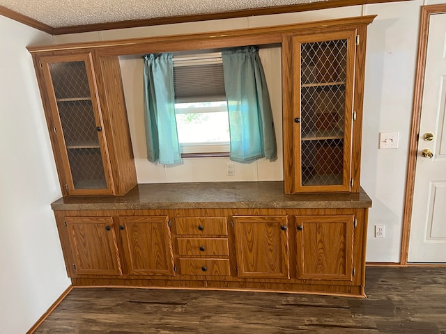 interior space featuring a textured ceiling, dark hardwood / wood-style floors, and crown molding