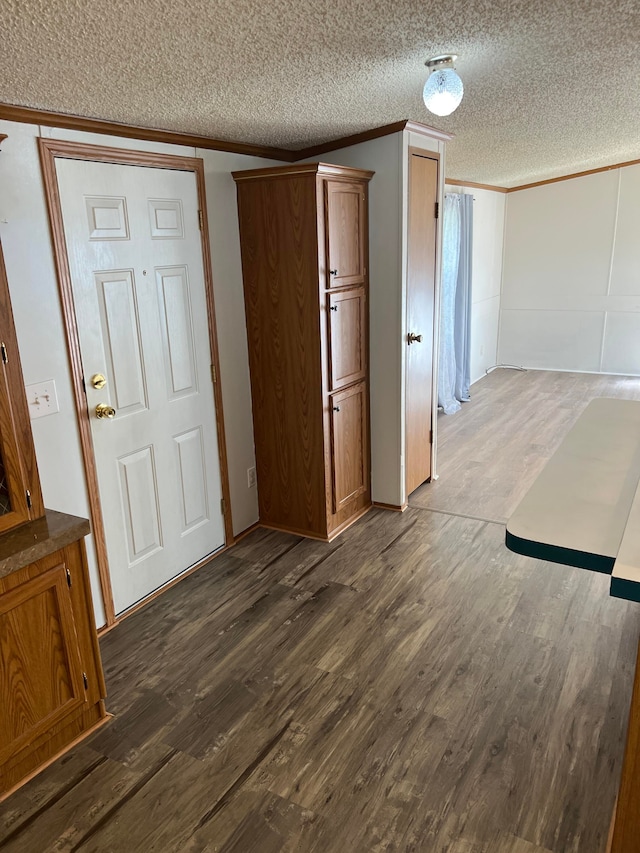 spare room with a textured ceiling, crown molding, and dark wood-type flooring