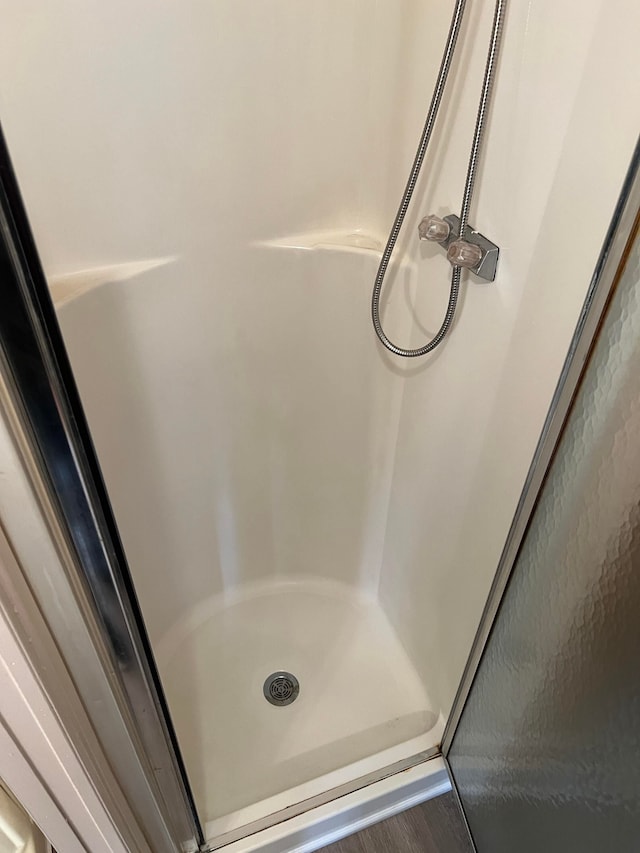 bathroom with hardwood / wood-style flooring and walk in shower