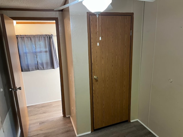 hallway with hardwood / wood-style flooring and a textured ceiling