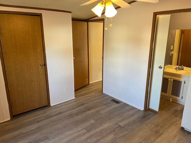 unfurnished bedroom with hardwood / wood-style floors, sink, ensuite bath, ceiling fan, and a textured ceiling