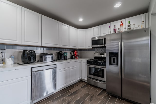 kitchen with white cabinetry, dark wood-type flooring, appliances with stainless steel finishes, and tasteful backsplash