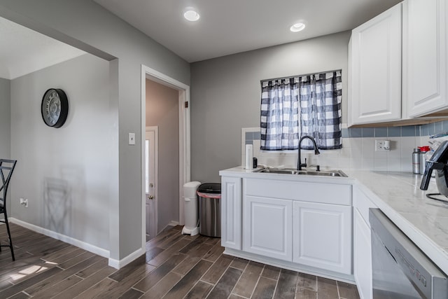 kitchen featuring tasteful backsplash, stainless steel dishwasher, dark wood-type flooring, sink, and white cabinets