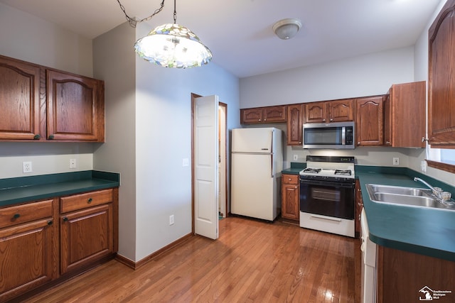 kitchen featuring sink, hardwood / wood-style flooring, hanging light fixtures, and white appliances