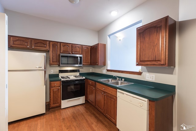 kitchen with light wood-type flooring, sink, and white appliances