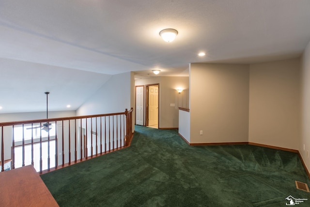 spare room with dark colored carpet and lofted ceiling