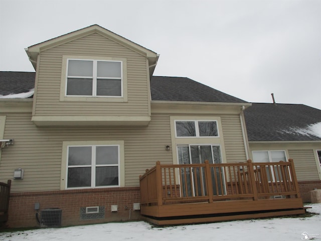 snow covered house featuring cooling unit and a wooden deck