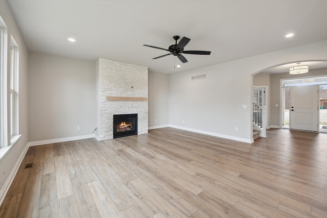 unfurnished living room featuring visible vents, light wood-style flooring, recessed lighting, arched walkways, and baseboards