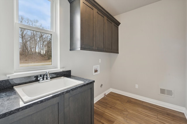 laundry room with visible vents, a sink, dark wood-style floors, cabinet space, and hookup for a washing machine