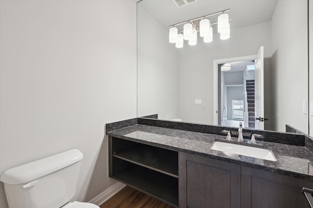 bathroom with visible vents, toilet, wood finished floors, baseboards, and vanity