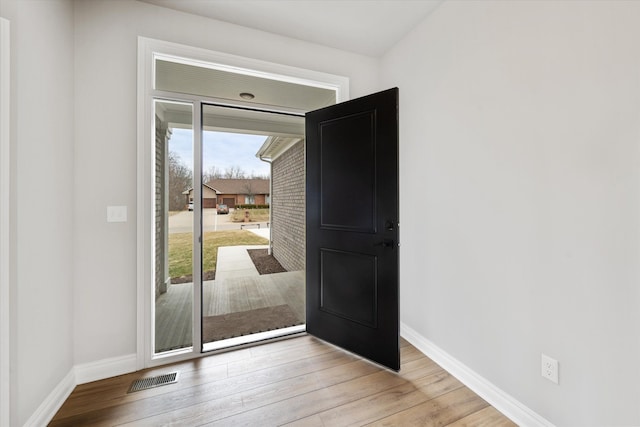 doorway with visible vents, baseboards, and light wood finished floors