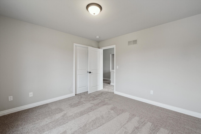 carpeted empty room with visible vents and baseboards