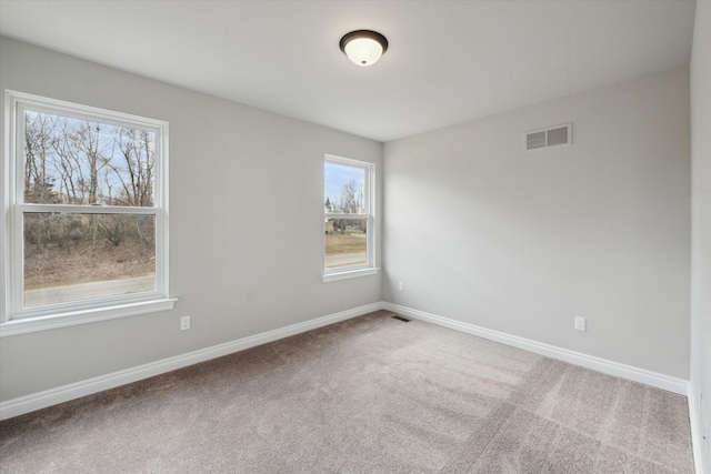 empty room featuring visible vents, carpet flooring, and baseboards