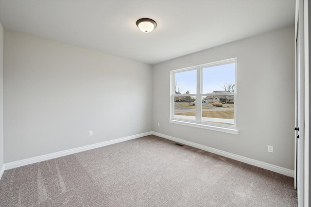 carpeted spare room with visible vents and baseboards