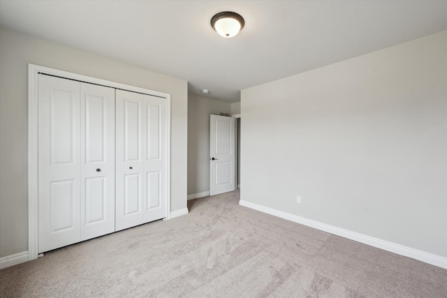 unfurnished bedroom with a closet, baseboards, and carpet flooring