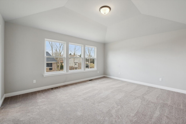 carpeted empty room featuring lofted ceiling, visible vents, and baseboards