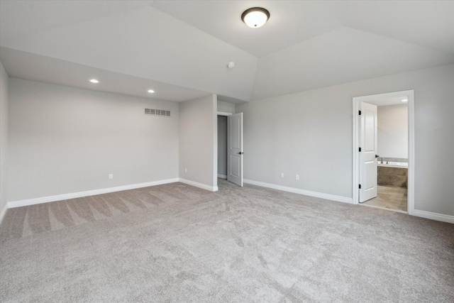 unfurnished bedroom featuring visible vents, baseboards, carpet, vaulted ceiling, and ensuite bath