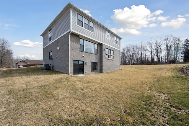 back of property with central air condition unit, a yard, and brick siding